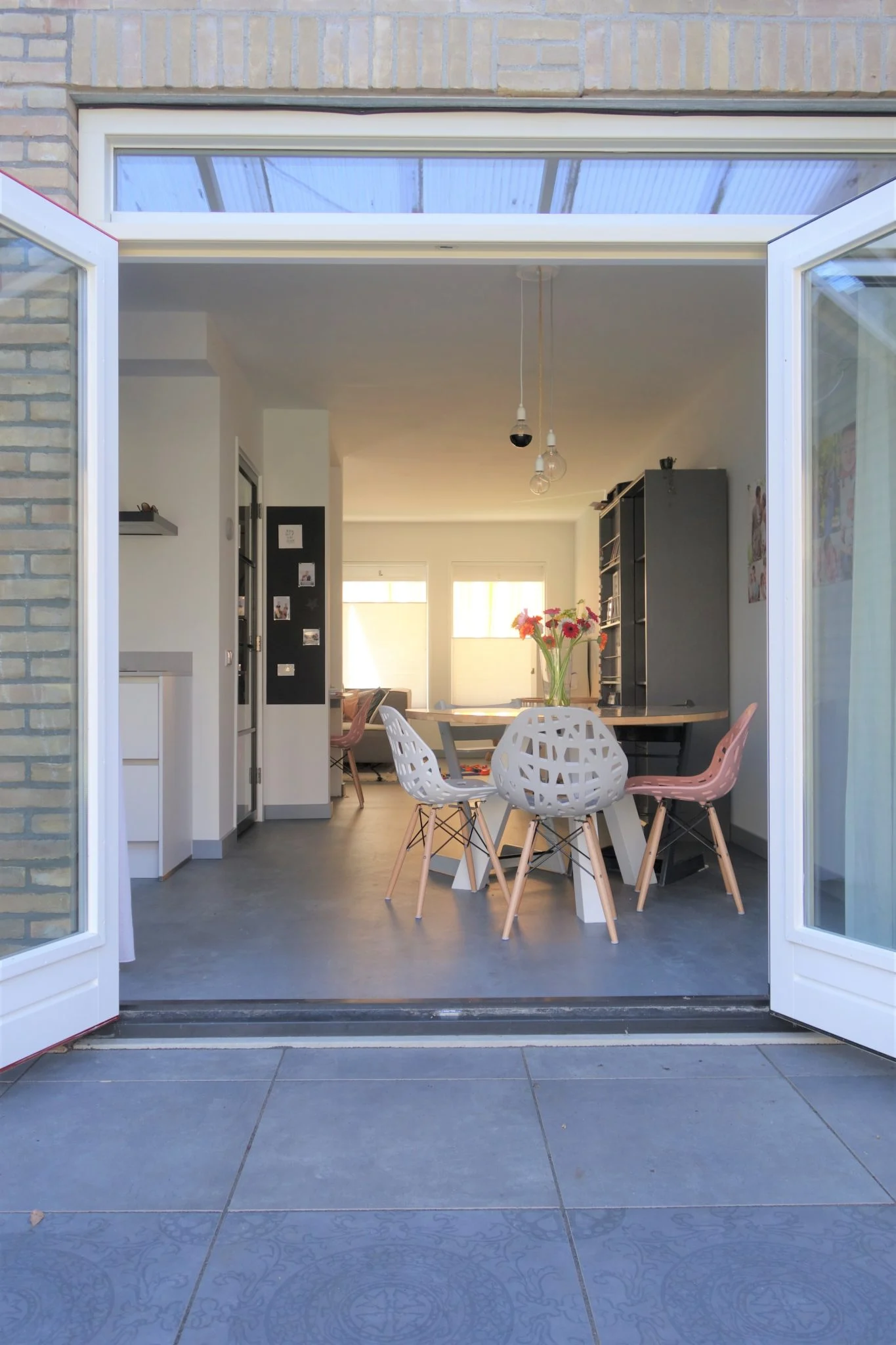 Binnenzicht door volledig geopende dubbele tuindeuren met vlakke dorpel en uitzicht op moderne woonkeuken – Toelevering Online