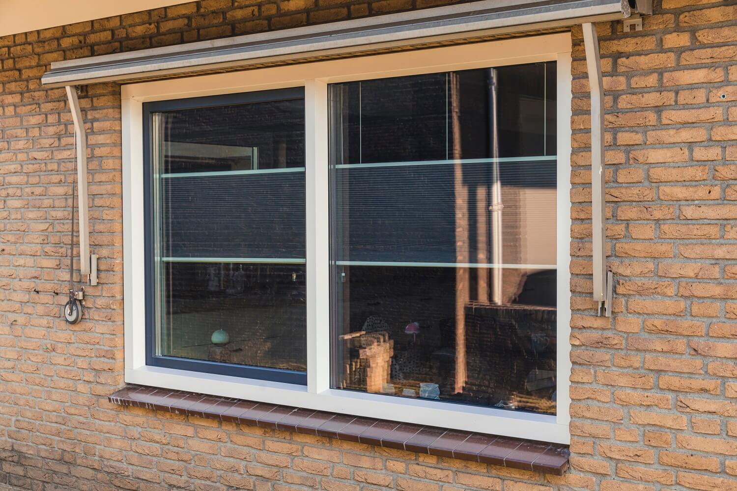 Kunststof raamkozijn met twee horizontale vakken en ingebouwde zonwering.