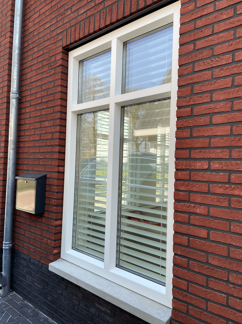 Wit houten raamkozijn met dubbel glas en nette afdichting tegen rood metselwerk voor optimale isolatie en afwerking – Toelevering Online